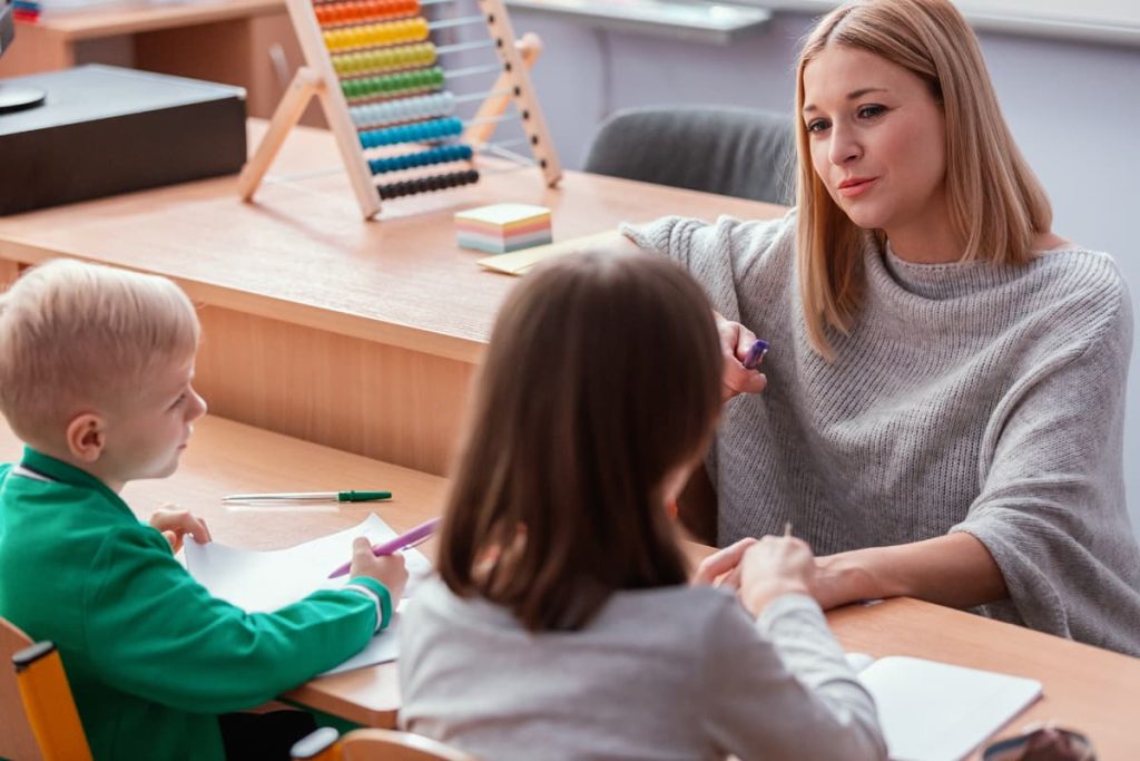 A therapist working with children in a classroom setting.