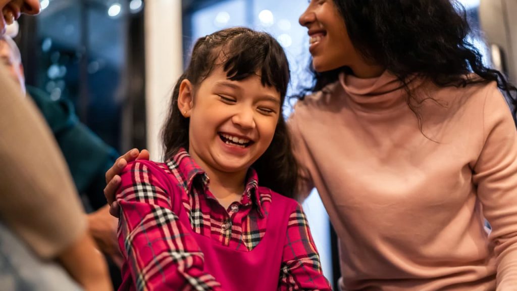 A child with Autism laughing with family.